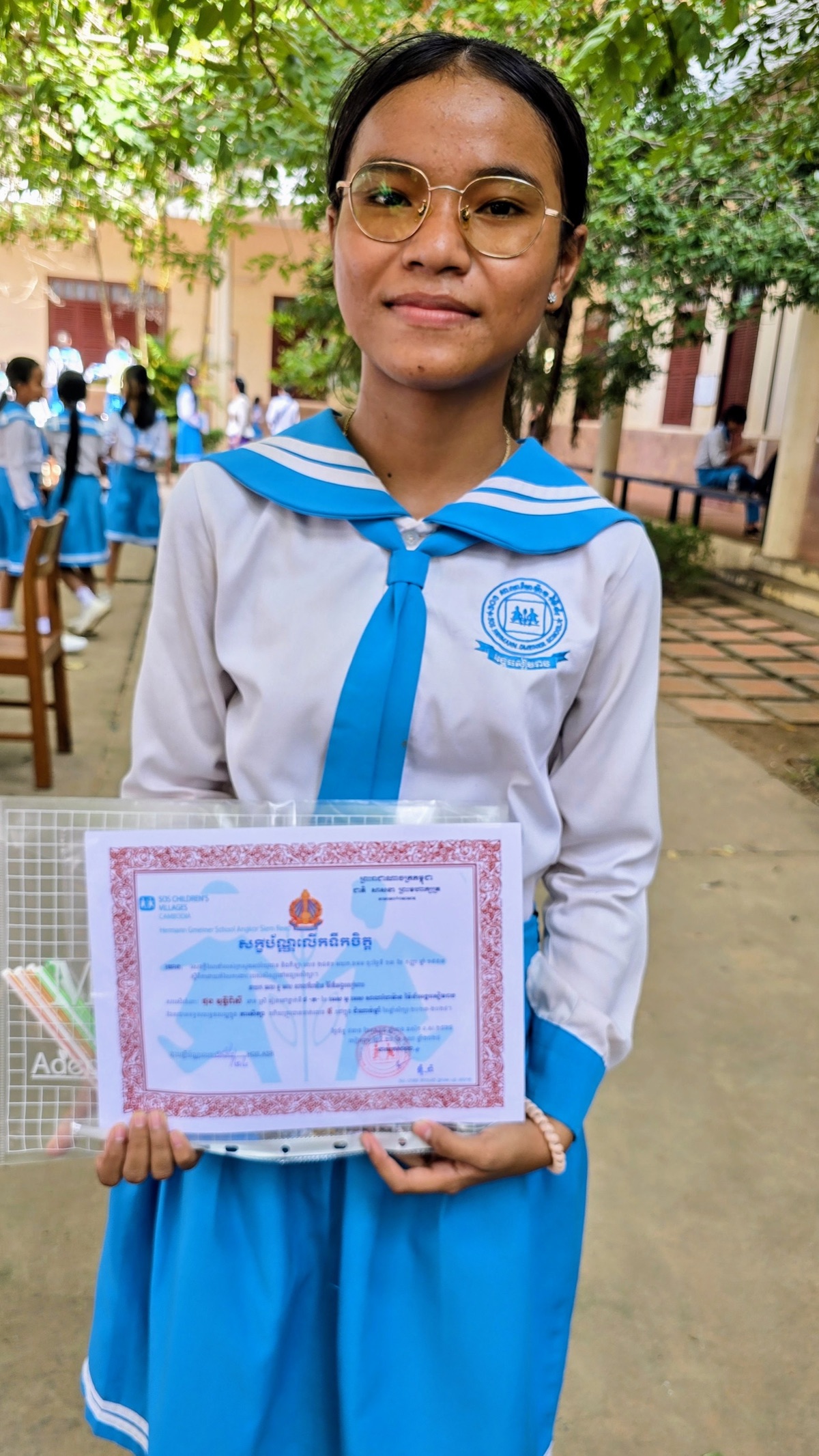 A student in school uniform holding her certificate