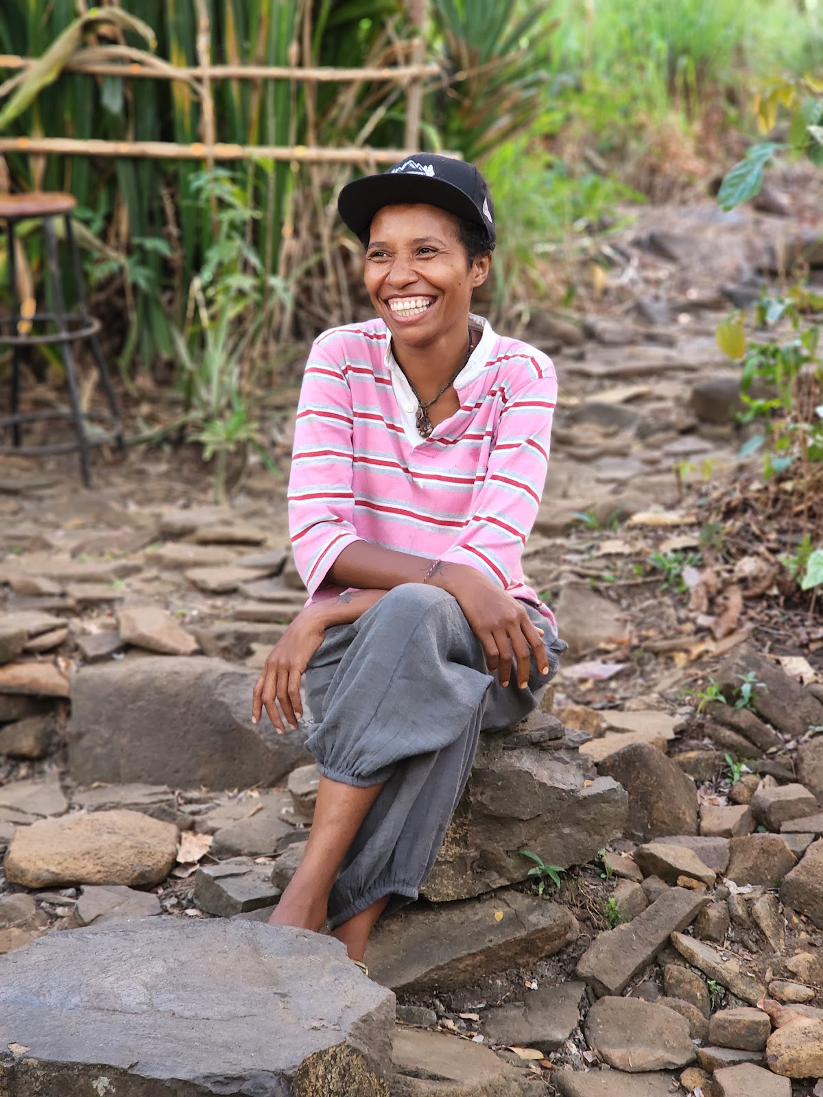 A smiling woman seated on a stone path