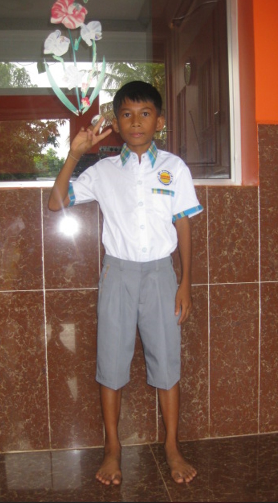 A boy in a new school uniform giving a peace sign
